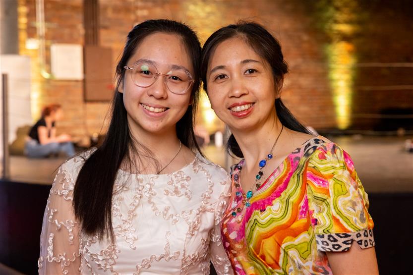 A woman wearing a white shirt and a woman wearing a multi-colored shirt smile